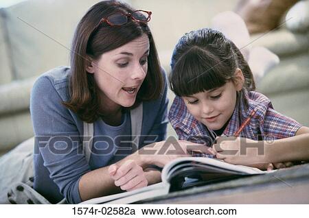 Stock Image - Mother assisting her daughter with her homework. Fotosearch