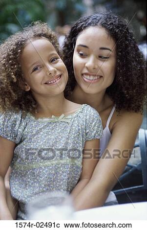 Stock Image - Mother hugging her daughter. Fotosearch