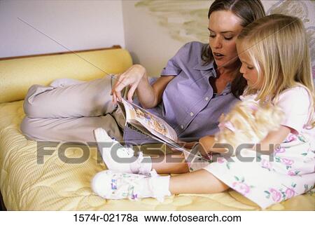 Stock Image - Mother reading a book with her daughter. Fotosearch