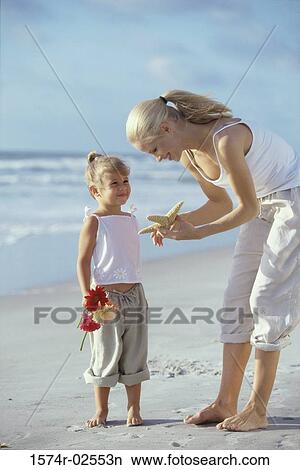 Picture - Mother showing her daughter a starfish on the beach. Fotosearch