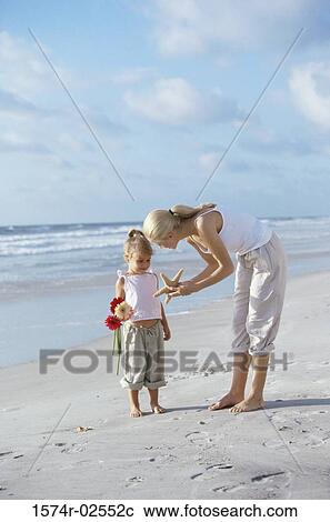 Mother showing her daughter a starfish on the beach View Large Photo Image Stock Image - Mother showing her daughter a starfish on the beach. Fotosearch