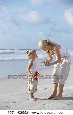 Mother showing her daughter a starfish on the beach View Large Photo Image Stock Image - Mother showing her daughter a starfish on the beach. Fotosearch