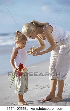 Mother showing her daughter a starfish on the beach View Large Photo Image Stock Image - Mother showing her daughter a starfish on the beach. Fotosearch