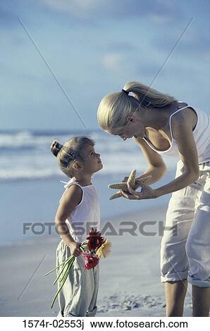 Mother showing her daughter a starfish on the beach View Large Photo Image Stock Image - Mother showing her daughter a starfish on the beach. Fotosearch