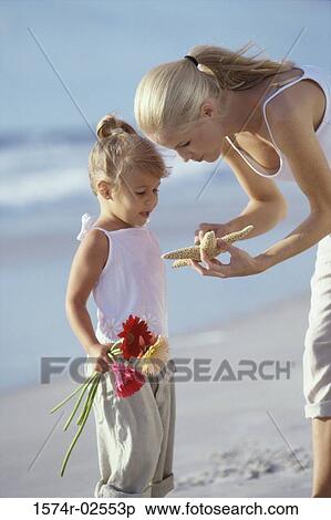 Stock Photography - Mother showing her daughter a starfish on the beach. Fotosearch
