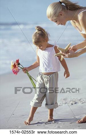 Stock Photography - Mother showing her daughter a starfish on the beach. Fotosearch