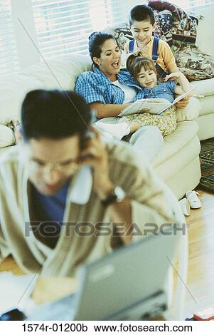 Stock Image - Mother sitting on the couch with her son and daughter. Fotosearch