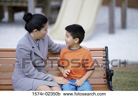 Mother sitting with her son on a park bench View Large Photo Image Stock Image - Mother sitting with her son on a park bench. Fotosearch