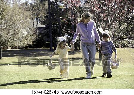 Stock Image - Mother walking on a lawn with her son and daughter. Fotosearch