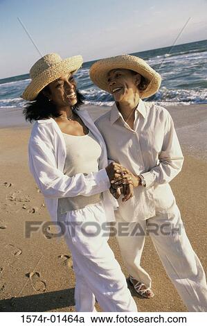 Stock Image - Mother walking with her daughter at the beach. Fotosearch