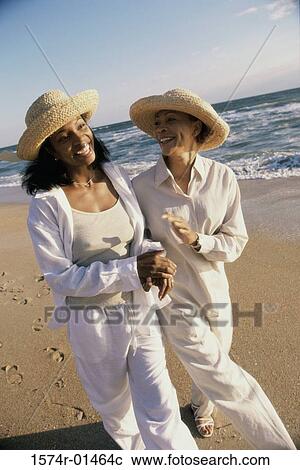 Stock Image - Mother walking with her daughter at the beach. Fotosearch