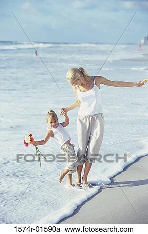 Stock Image - Mother walking with her daughter on the beach. Fotosearch