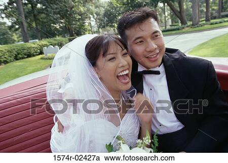 Stock Image - Newlywed couple sitting in a convertible car. Fotosearch