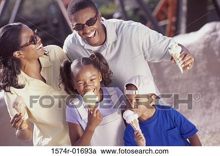Stock Image - Parents and their two children eating ice cream cones. Fotosearch