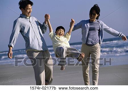 Parents carrying their son on the beach View Large Photo Image Stock Image - Parents carrying their son on the beach. Fotosearch