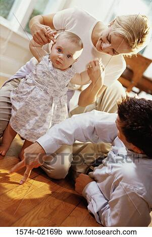 Parents helping their baby girl learn how to walk View Large Photo Image Stock Image - Parents helping their baby girl learn how to walk. Fotosearch