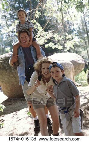 Stock Image - Parents hiking in the forest with their son and daughter. Fotosearch