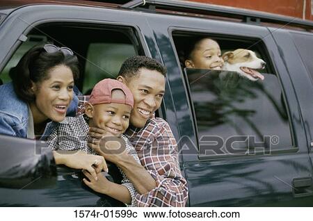 Stock Image - Parents in a car with their two children and a dog. Fotosearch