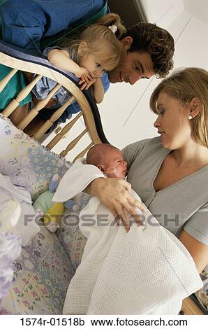 Stock Image - Parents looking at their baby girl in a crib. Fotosearch