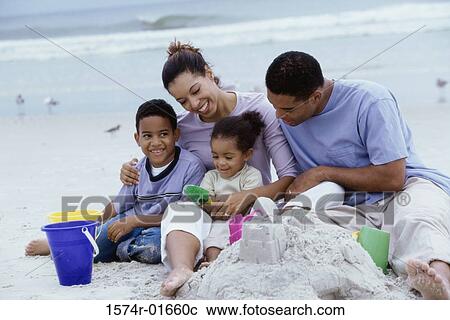 Stock Image - Parents playing with their son and daughter at the beach. Fotosearch