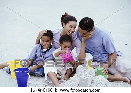 Stock Image - Parents playing with their son and daughter at the beach. Fotosearch