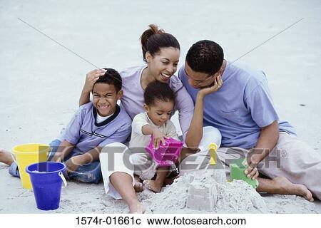 Stock Image - Parents playing with their son and daughter at the beach. Fotosearch
