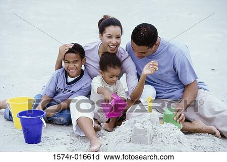 Stock Image - Parents playing with their son and daughter at the beach. Fotosearch