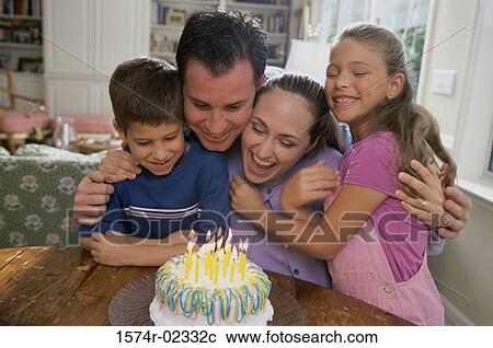 Stock Image - Parents with their son and daughter in front of a birthday cake. Fotosearch