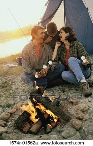 Stock Image - Parents with their son sitting in front of a campfire on the beach. Fotosearch