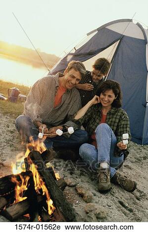 Stock Image - Parents with their son sitting in front of a campfire on the beach. Fotosearch