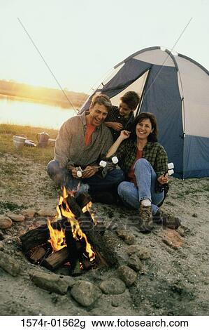 Stock Image - Parents with their son sitting in front of a campfire on the beach. Fotosearch