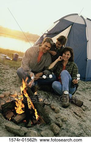 Stock Image - Parents with their son sitting in front of a campfire on the beach. Fotosearch