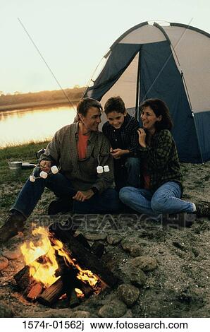 Stock Image - Parents with their son sitting in front of a campfire on the beach. Fotosearch
