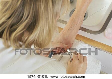Stock Image - Pedicurist clipping a person's toenails. Fotosearch