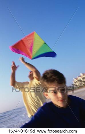 Stock Image - Portrait of a boy boy flying a kite with his father at the beach. Fotosearch