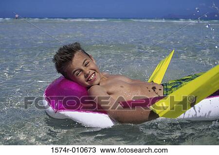 Portrait of a boy floating on water at the beach View Large Photo Image Stock Image - Portrait of a boy floating on water at the beach. Fotosearch