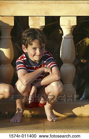 Portrait of a boy squatting in front of a banister View Large Photo Image Stock Image - Portrait of a boy squatting in front of a banister. Fotosearch
