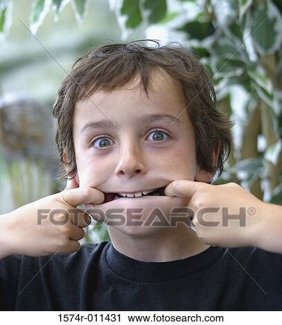Stock Image - Portrait of a boy stretching the sides of his mouth. Fotosearch