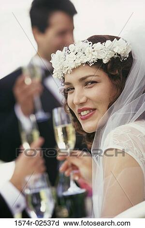 Stock Image - Portrait of a bride toasting with glasses of champagne. Fotosearch
