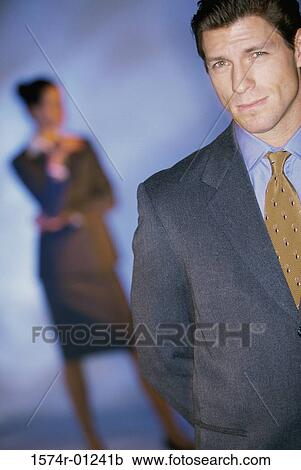 Portrait of a businessman smiling with a businesswoman behind him View Large Photo Image Stock Image - Portrait of a businessman smiling with a businesswoman behind him. Fotosearch