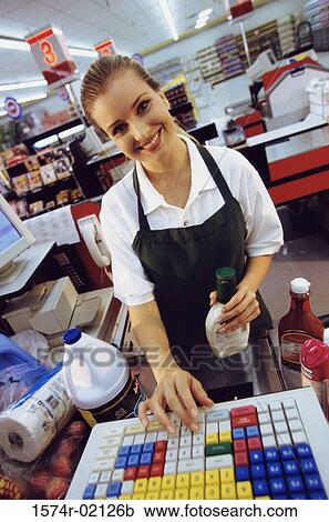 Stock Image - Portrait of a cashier standing at a checkout counter in a supermarket. Fotosearch