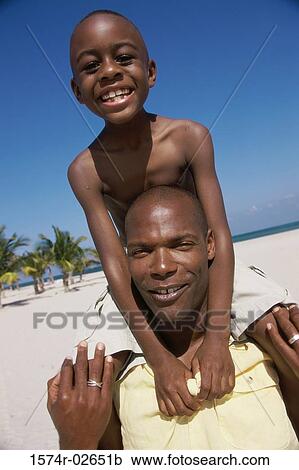 Stock Image - Portrait of a father carrying his son on his shoulder. Fotosearch