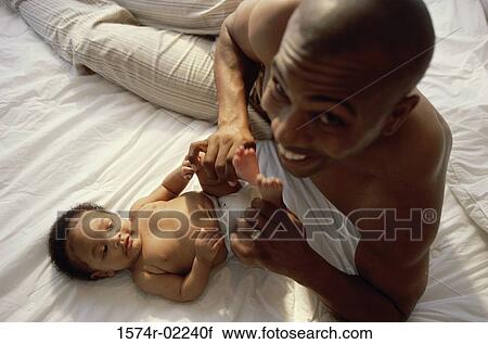 Stock Image - Portrait of a father holding his baby boy's feet. Fotosearch