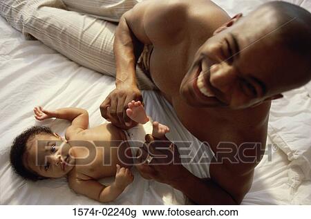 Stock Image - Portrait of a father holding his baby boy's feet. Fotosearch