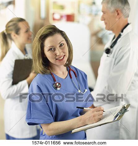 Stock Photograph - Portrait of a female nurse holding a clipboard. Fotosearch