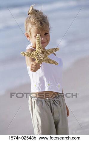 Portrait of a girl holding a starfish on the beach View Large Photo Image Stock Image - Portrait of a girl holding a starfish on the beach. Fotosearch