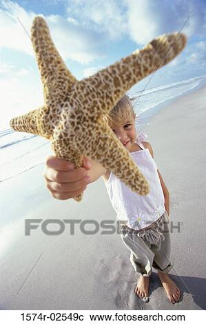 Portrait of a girl holding a starfish on the beach View Large Photo Image Stock Image - Portrait of a girl holding a starfish on the beach. Fotosearch