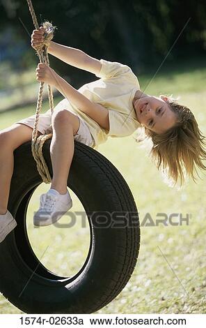 Stock Image - Portrait of a girl sitting on a tire swing. Fotosearch