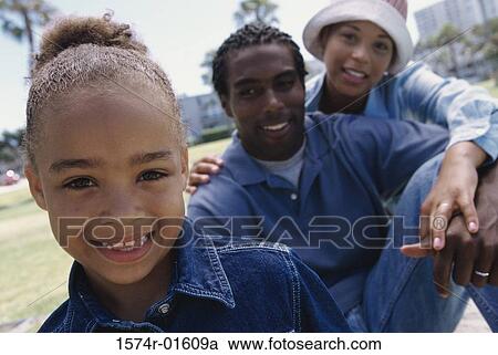 Stock Image - Portrait of a girl sitting with her parents. Fotosearch