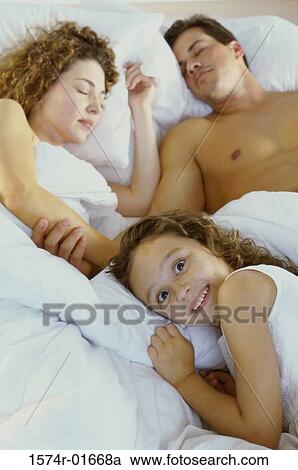 Portrait of a girl smiling with her parents sleeping behind her View Large Photo Image Stock Image - Portrait of a girl smiling with her parents sleeping behind her. Fotosearch